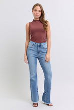 Load image into Gallery viewer, Woman standing against a light gray background, wearing a sleeveless brown top and light blue flared jeans, with a casual, confident pose.